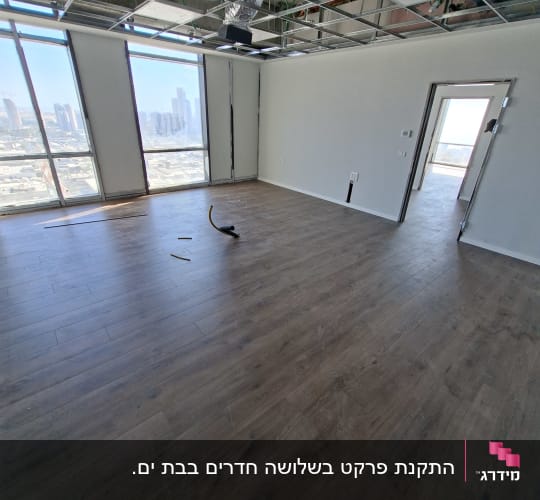 רצפת פרקט בחדר ריק עם חלונות גדולים